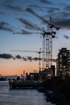 Silhouette of tower cranes during sunset over New Westminster waterfront.
