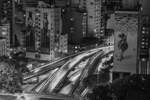 Aerial view of São Paulo cityscape with illuminated roads and building murals at night.