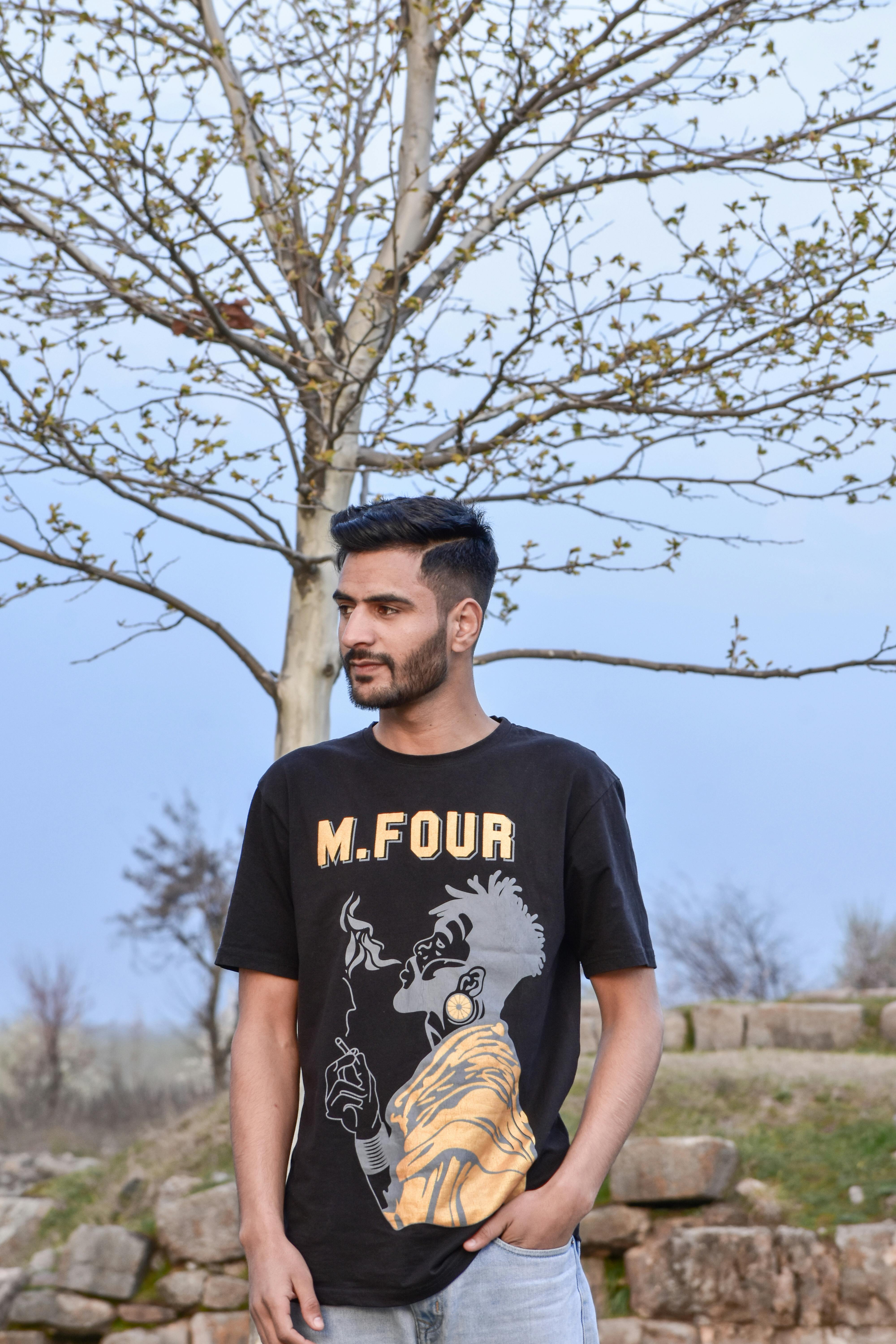 Young man outdoors wearing a graphic t-shirt against a spring backdrop.
