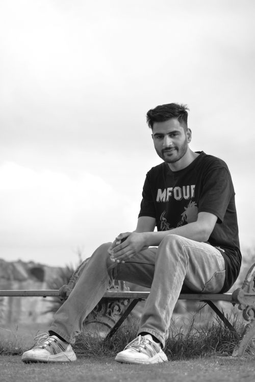 Free Black and white portrait of a smiling man sitting on a park bench outdoors. Stock Photo