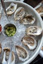不锈钢碗中新鲜牡蛎的顶视图，盛在碎冰上，配上调味品