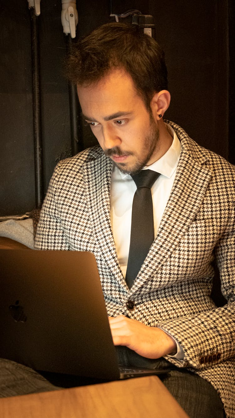 A Man In Black And White Plaid Suit Jacket Using Laptop 