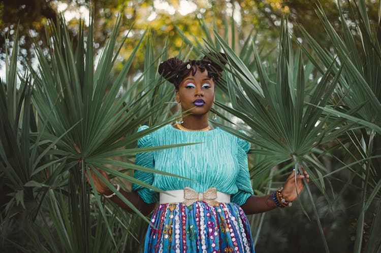 Woman In A Blue Blouse And Multicolored Skirt Posing With Palmetto Leaves