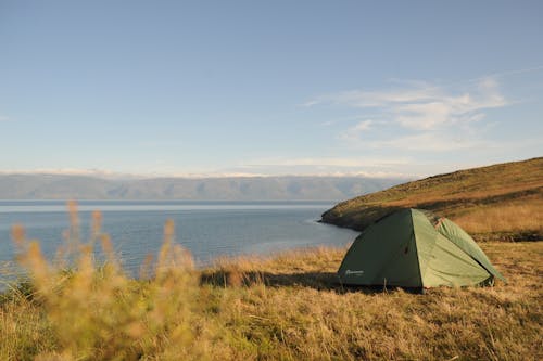 Green Tent on Green Grass Field Near Body of Water