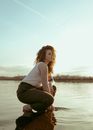 Woman with Curly Red Hair Crouching in Shallow Lake Water