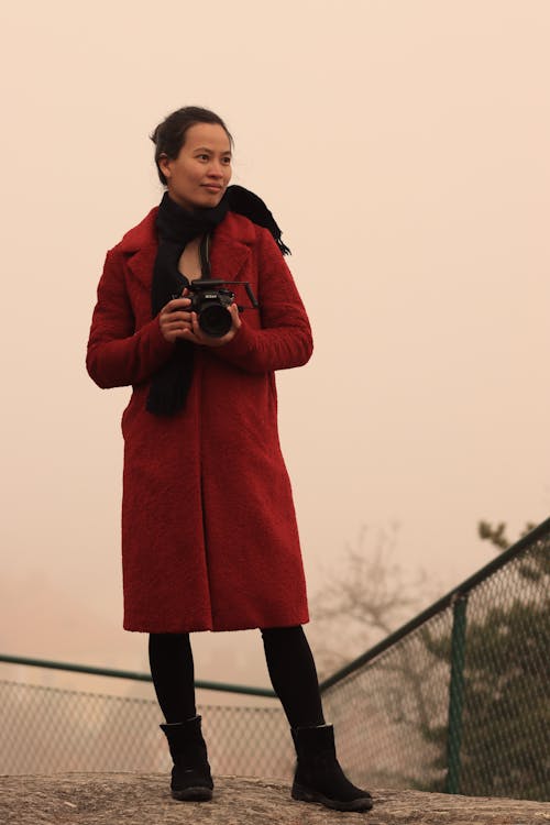Woman in Red Coat Holding a Camera