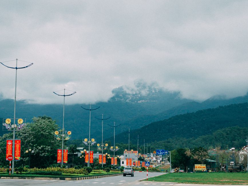 Picturesque road in Vinh Phuc, Vietnam with mountainous backdrop and colorful street banners.