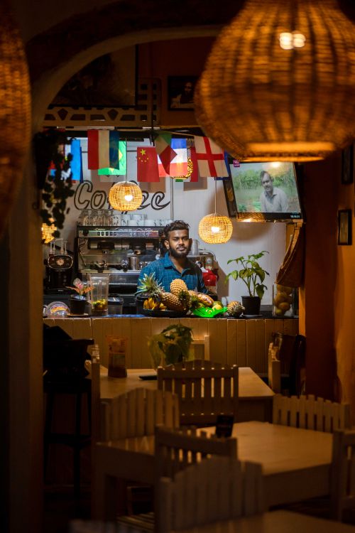Free A cozy restaurant features a bearded man behind the counter, vibrant flags, and warm lighting. Stock Photo