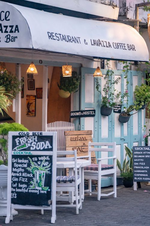 Free Cozy outdoor seating at a cafe with chalkboard menu, plants, and inviting ambiance. Stock Photo