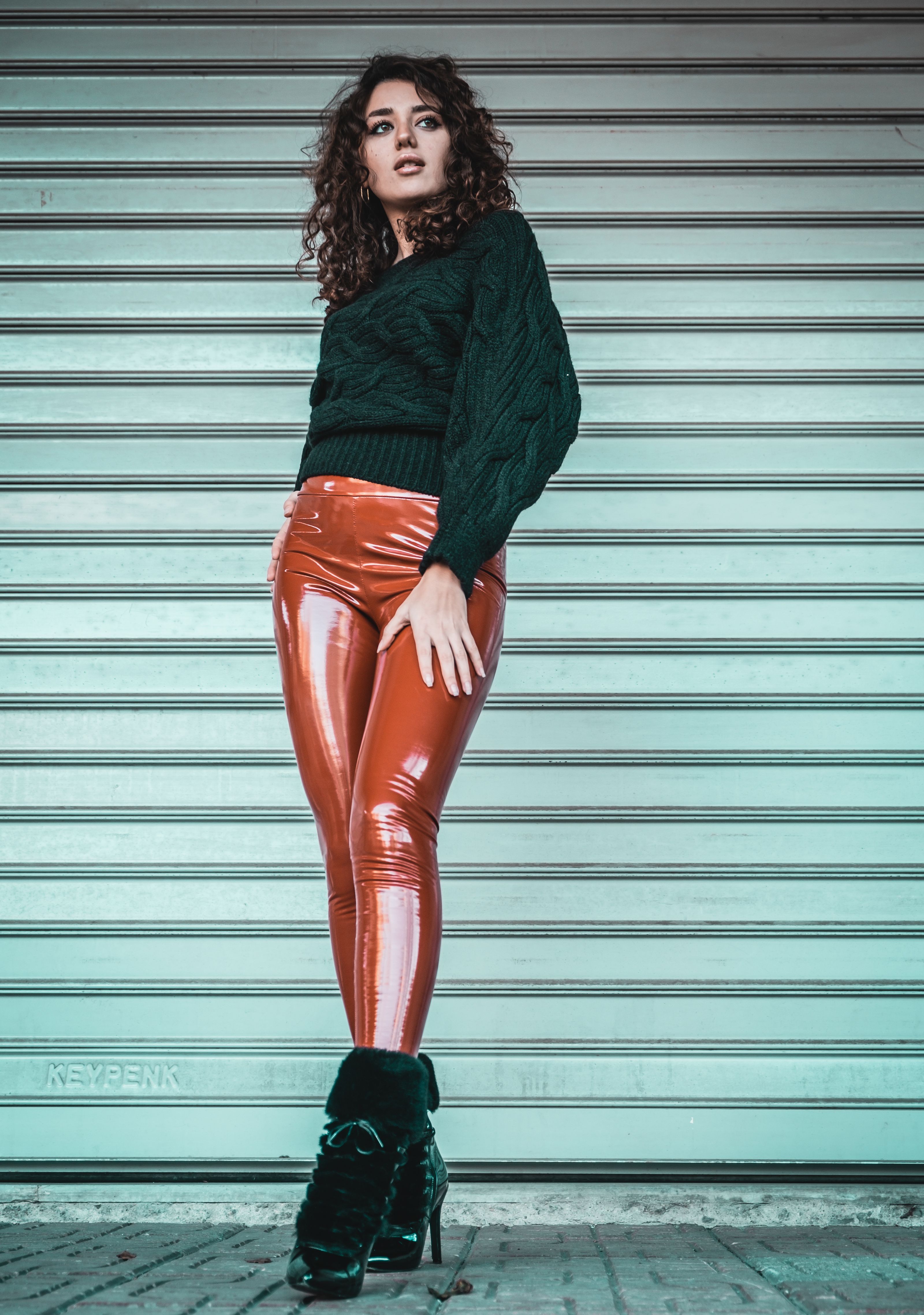 Mulher fashion posando em leggings brilhantes contra um portão de enrolar em Istambul.