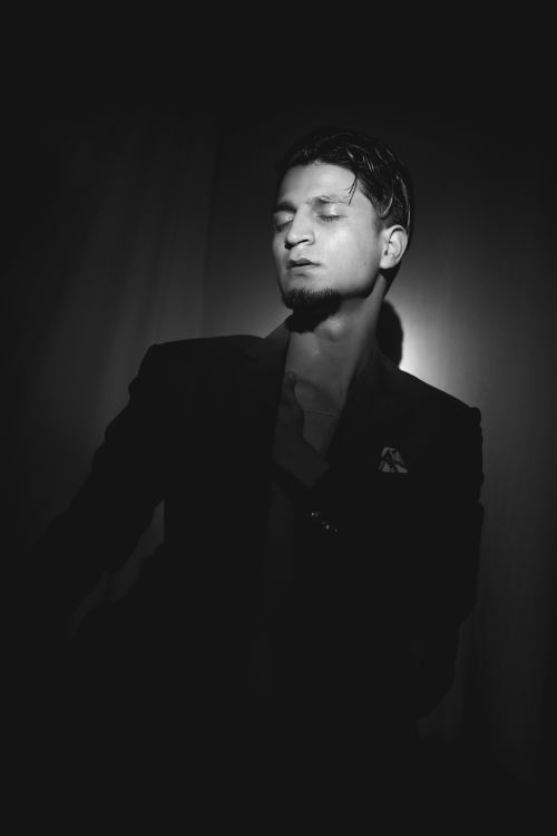 Free Striking black and white portrait of a man in a suit with eyes closed, exuding elegance and mystery. Stock Photo
