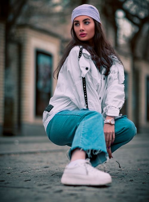 Free A woman in a white jacket and jeans, squatting on a street in Tehran, Iran. Stock Photo