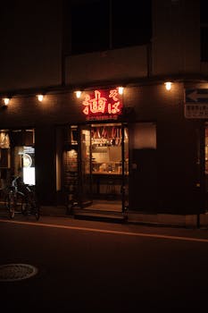Warmly lit restaurant entrance at night with neon signage, bicycle parked outside.