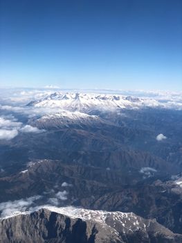 Breathtaking aerial photo of snow-capped mountains under a clear blue sky.