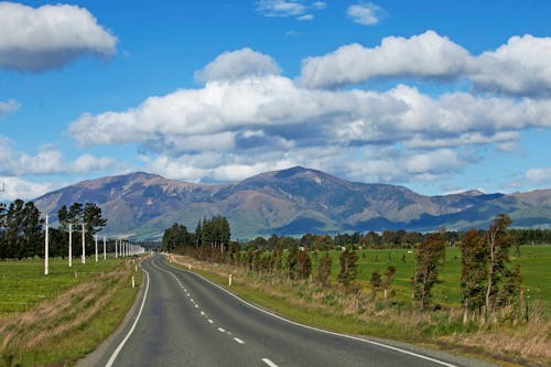 Free Asphalt Road and Mountains under the Cloudy Blue Sky Stock Photo