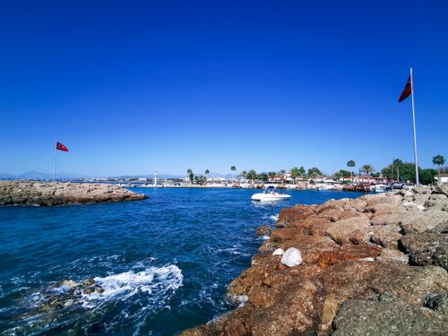 Free Picturesque Turkish coastline with boats and rocky shore under clear blue skies. Stock Photo