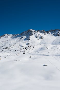 A breathtaking aerial view of a snow-covered mountain landscape beneath a clear blue sky, ideal for nature and travel themes.