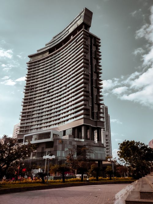 Free A modern high-rise building with a unique curved design set against a clear blue sky. Stock Photo