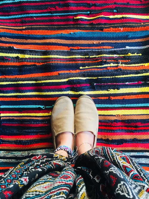 Person Wearing Brown Shoes Standing on Colorful Stripe Rug