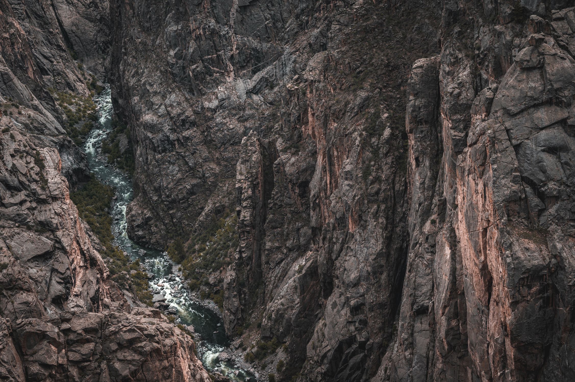 Aerial view of the rugged Black Canyon showcasing dramatic geological formations and a flowing river.