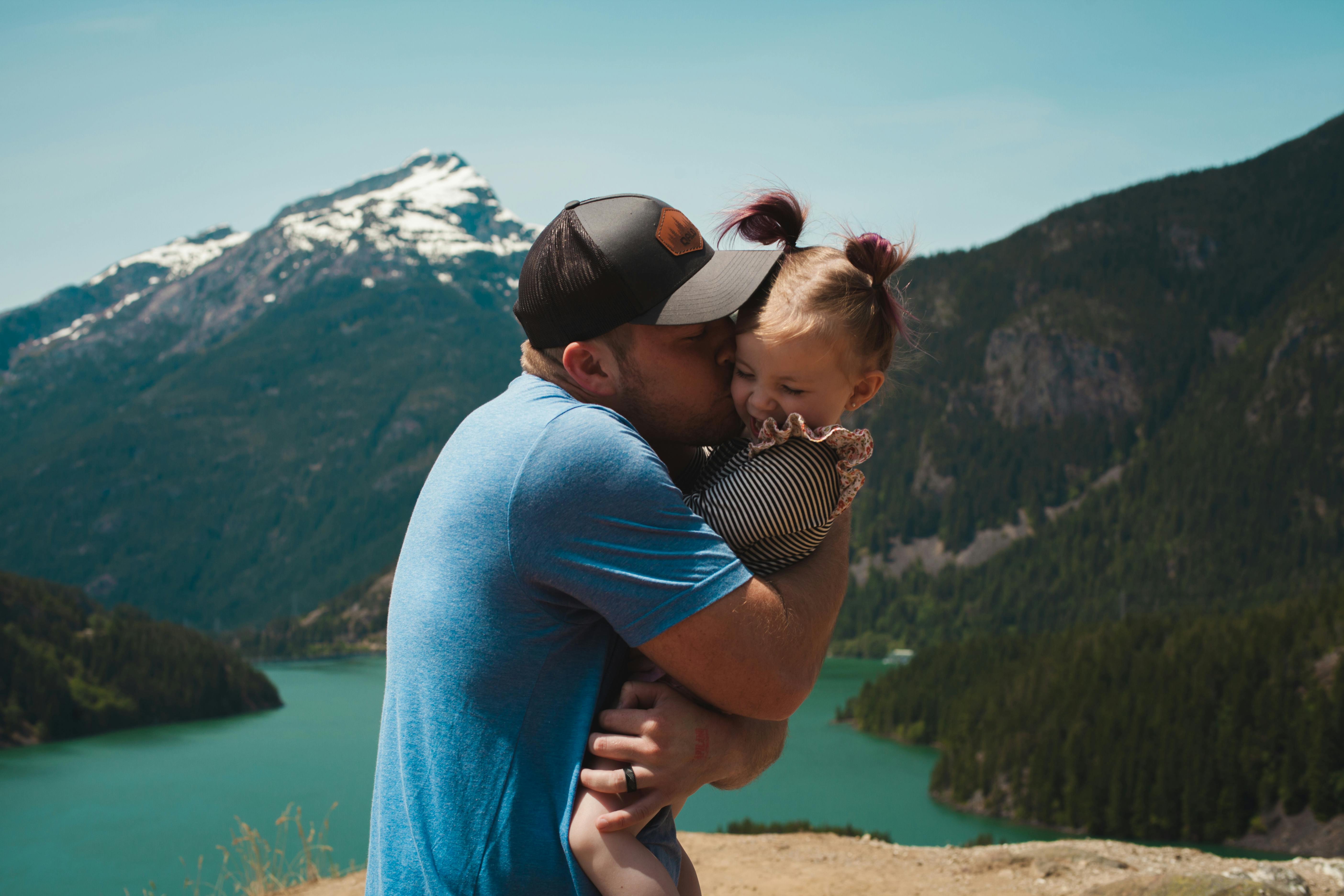 Un père et une petite fille qui s'amusent près des montagnes. | Photo : Pexels