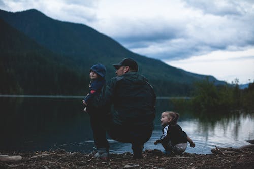 Free Man With Two Kids Near Body of Water Stock Photo