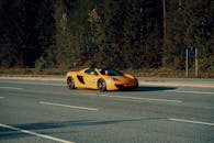 在加拿大惠斯勒的高速公路上，一辆黄色跑车正飞驰在一个阳光明媚的日子里