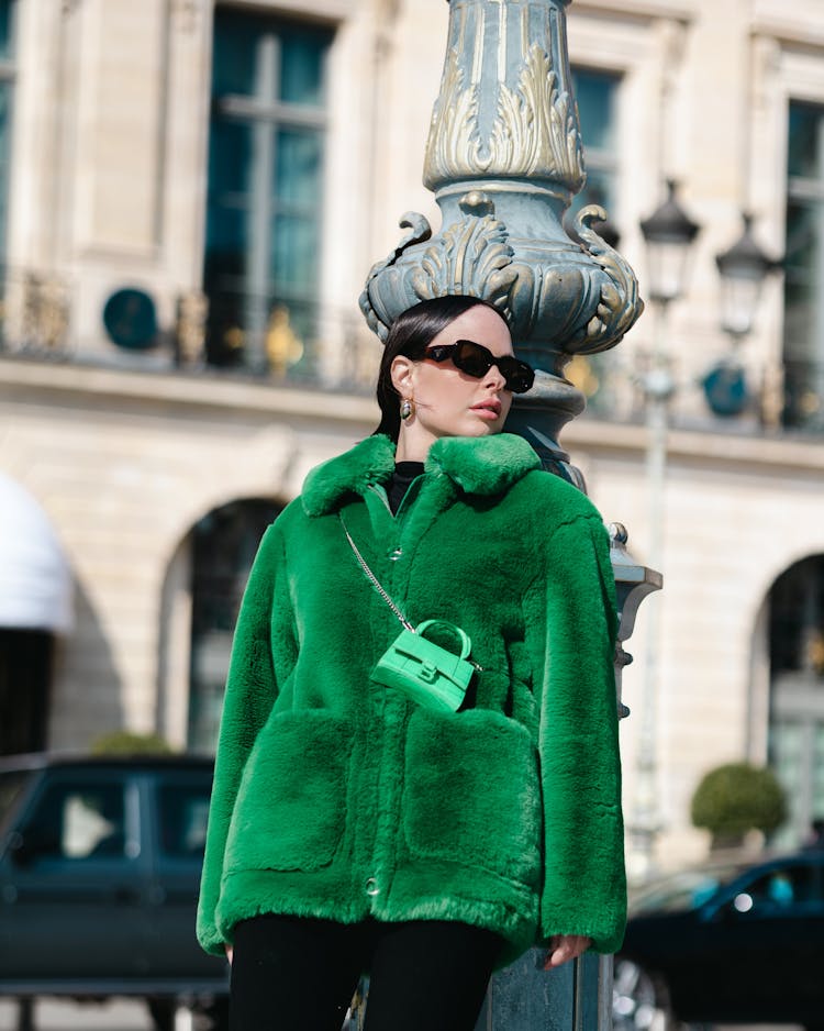 Pretty Woman In Green Jacket Leaning On A Pole