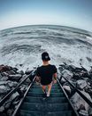 Man in Black T-shirt and Brown Shorts Standing on Gray Staircase