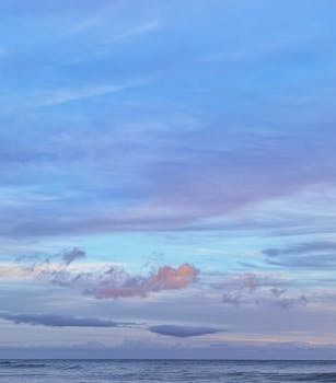 Tranquil seascape of the ocean meeting the blue sky with pastel clouds in Portimão, Portugal.