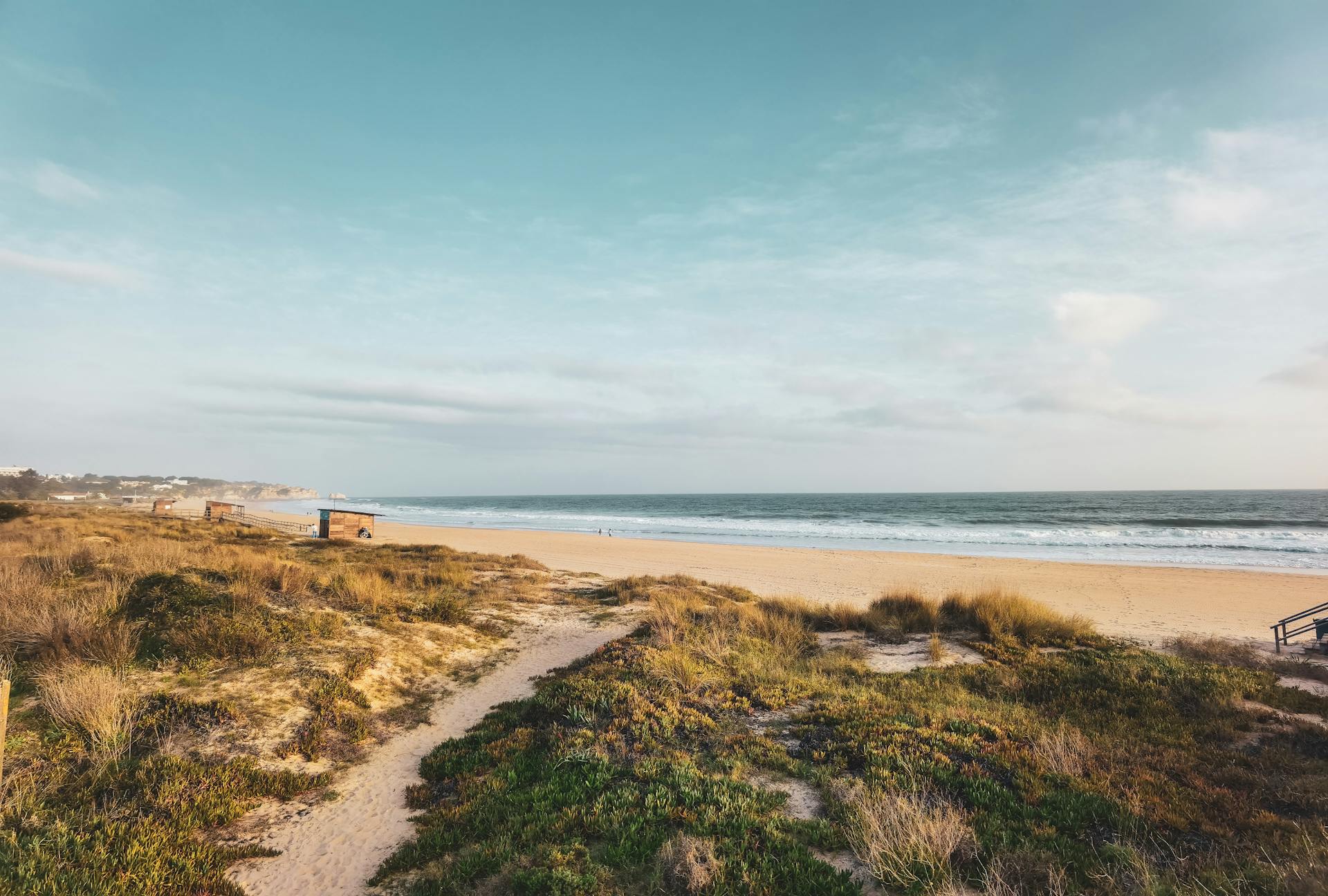 Experience the serene beauty of a Faro coastal beach, capturing the ocean, sand, and sky with a scenic view.