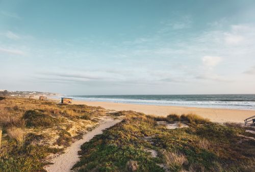Free Experience the serene beauty of a Faro coastal beach, capturing the ocean, sand, and sky with a scenic view. Stock Photo