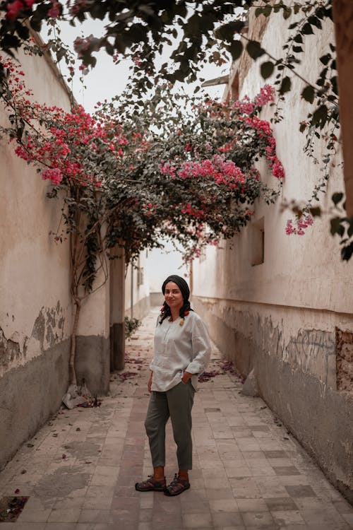 A Woman in White Long Sleeves Standing on the Street Between Concrete Walls