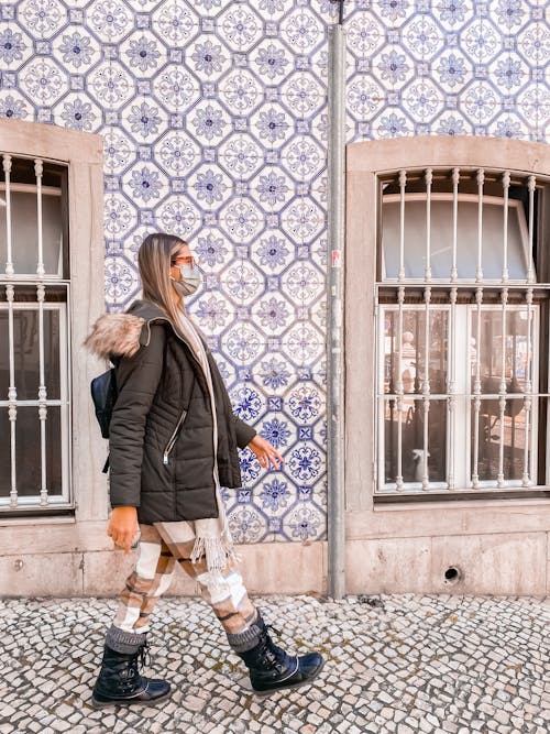 Free A Person in a Face Mask and  Warm Clothing Walking on a Sidewalk Stock Photo