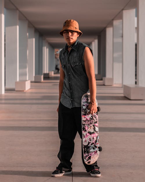 A Young Man in a Trendy Outfit Posing with a Skateboard
