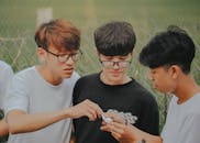 三个十几岁的男孩在外面一起看手机，享受着一段轻松的时光