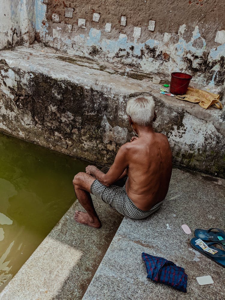 Old Man Sitting On Stairs Near Water