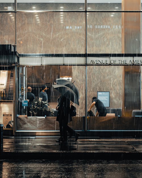 People Walking on Sidewalk with Umbrellas in City