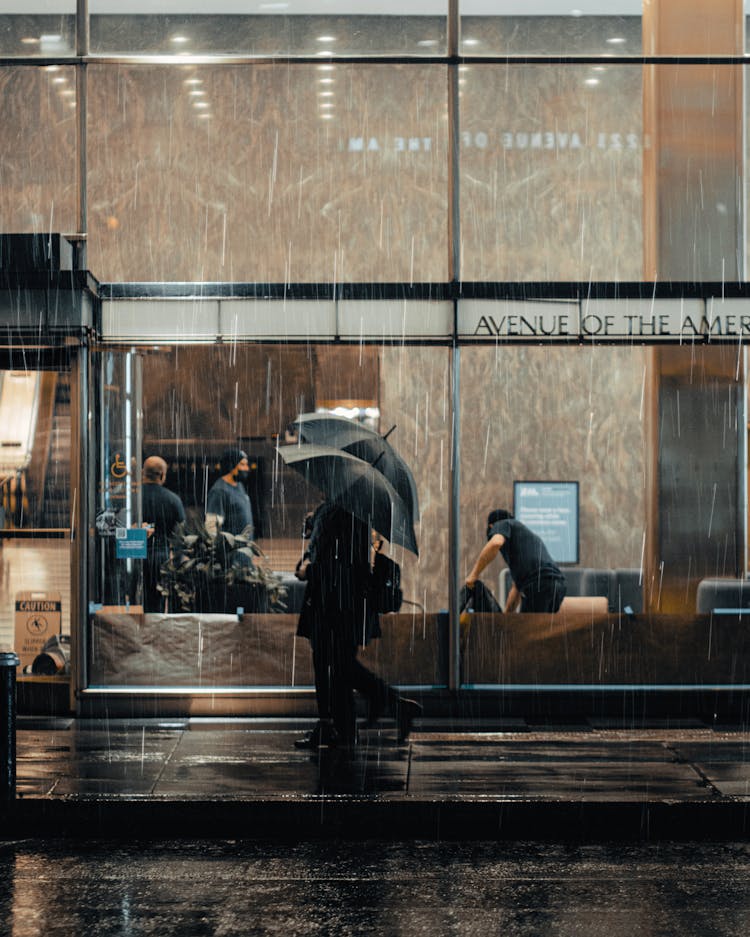 People Walking On Sidewalk With Umbrellas In City