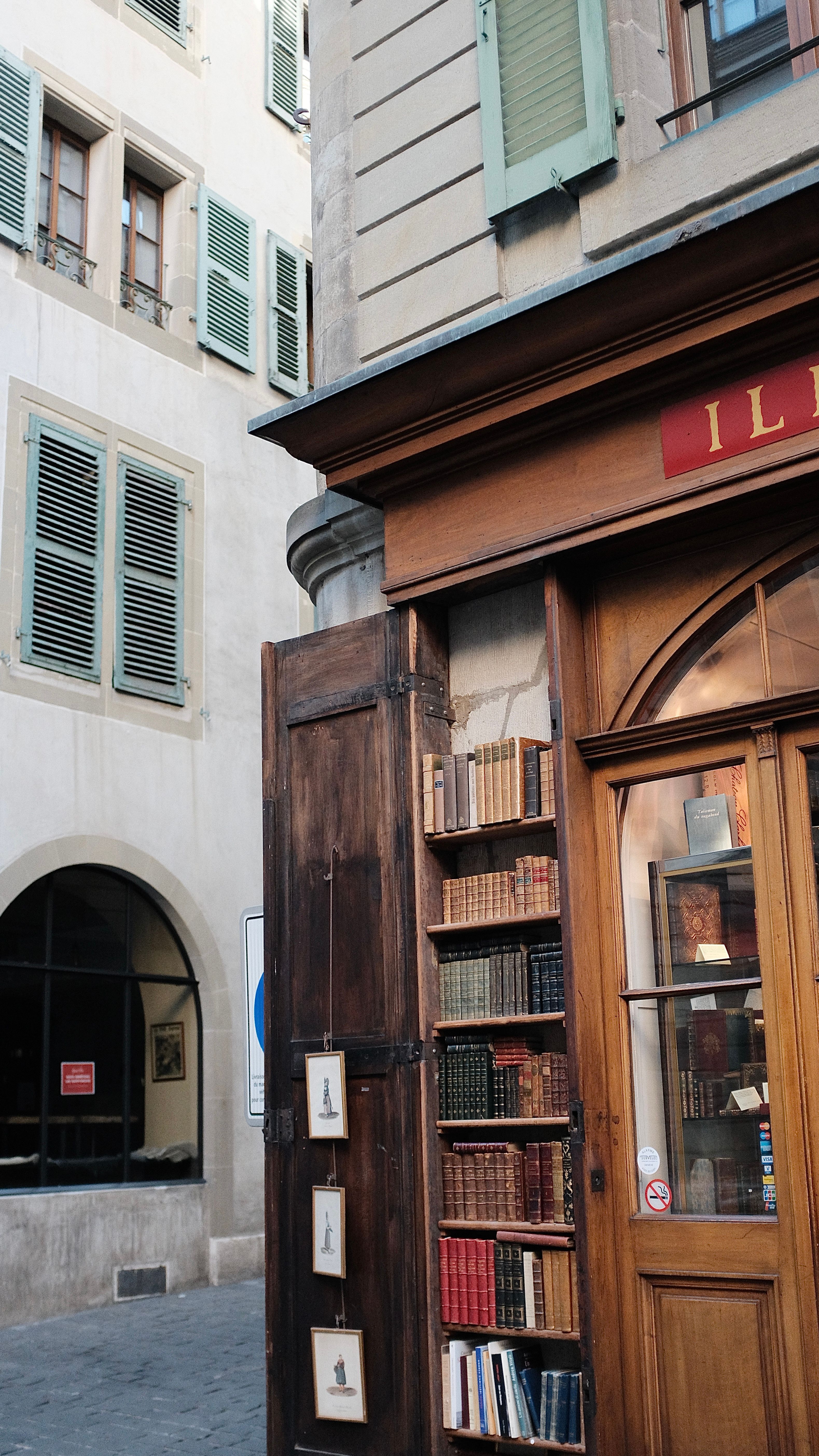 Quaint bookstore facade with books on display in Geneva's historical district under soft daylight.