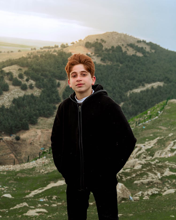 Boy Standing On Hill In Mountains Landscape