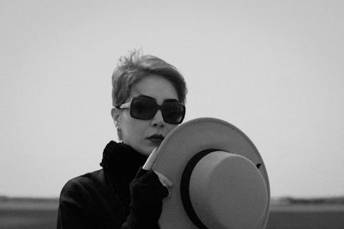 Woman Wearing Sunglasses Holding a Hat