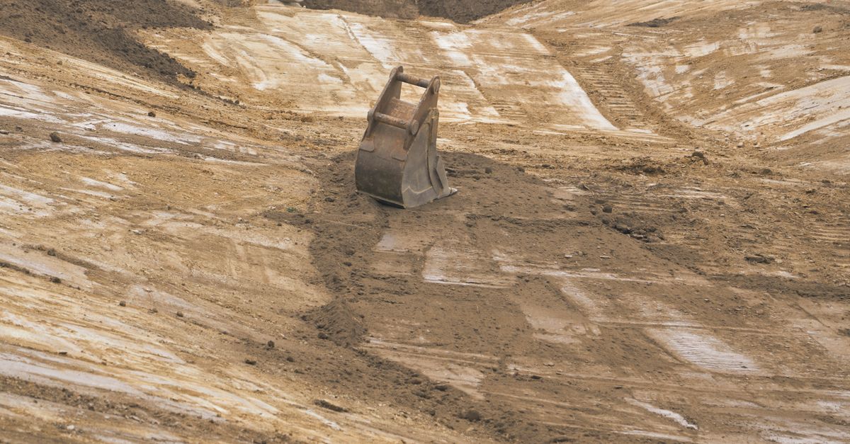 Baggerschaufel auf einem Erdaushub-GrundstĂĽck als Symbol fĂĽr Bodenuntersuchungen und Altlastensanierung.