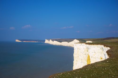 Free Serene view of the iconic Seven Sisters cliffs against a blue sky in Eastbourne, UK. Stock Photo