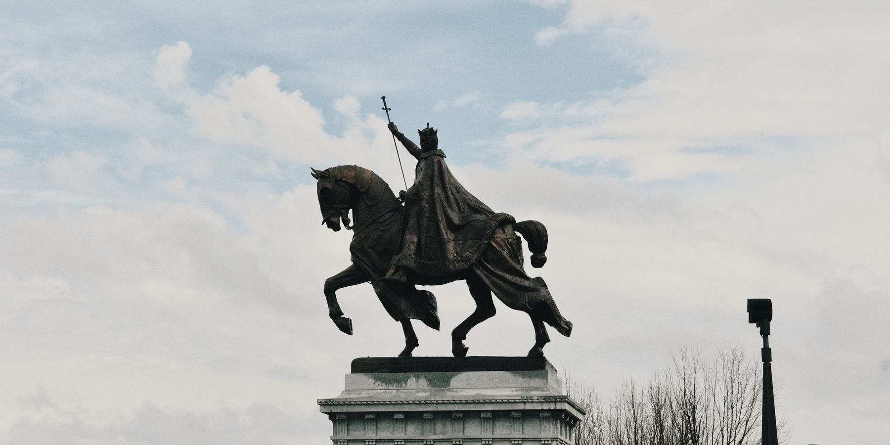 Equestrian statue of King Louis IX in St. Louis, Missouri under a partly cloudy sky.