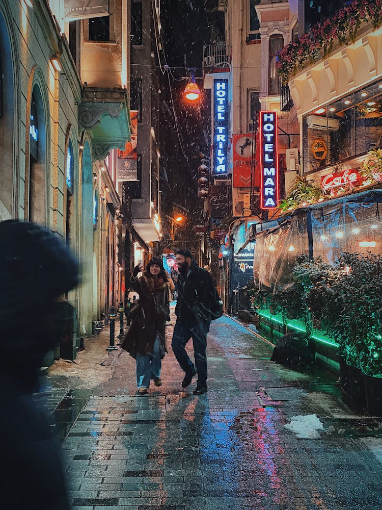 Couple Walking On Sidewalk On A Snowy Night