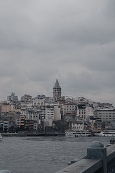 Atmospheric cityscape of Istanbul with the historic Galata Tower under overcast skies.