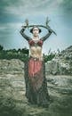 Woman Wearing Black and Red Dress Holding Sword Standing on Rock Surface during Day Time