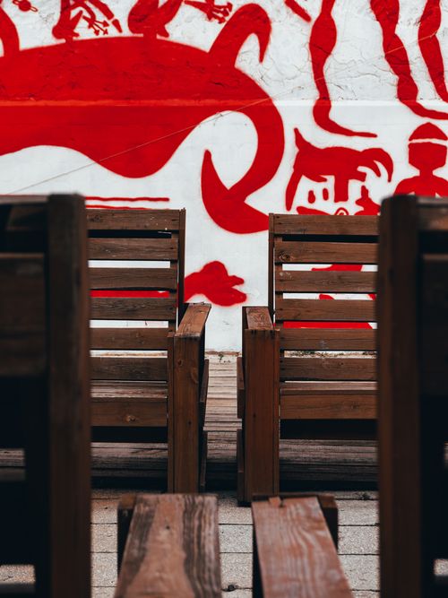 Free Wooden chairs arranged in front of a vibrant red mural in Kyiv's art district. Stock Photo