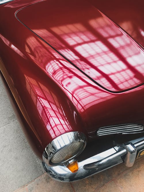 Close Up of Lights Reflecting on Red Car Hood